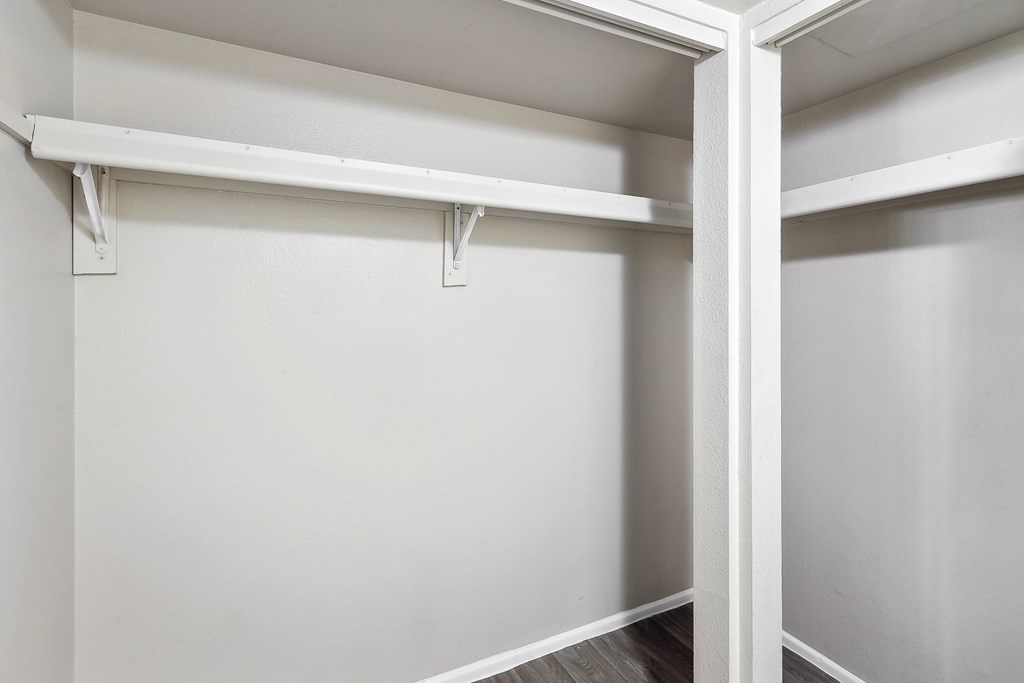 an empty closet in a home with white walls and wood floors